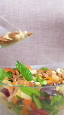 Kadın yavaşça fındık ekliyor fındıklı salata badem eldiven giymiş kadın önlük pişiriyor sebze malzemelerini masaya koyuyor sağlıklı yiyecekler vejetaryen yemekleri 