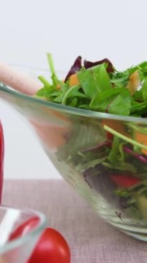Masa bej masa örtüsünün üzerinde cam kasede yakın plan vejetaryen yiyecekler badem, fındık, fındık, zeytin, biber, ahşap kaşıklarla pişirilmiş taze salata. 