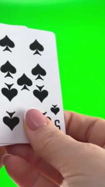 Fransız manikürlü kadın elleri. Kadın kartları düzenler, katlar gibi inceler ve yelpaze gibi yayılır aynı takımın dört kart sol elinde yeşil bir arka planda dört dokuzlu tutar