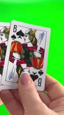 Yeşil arka planda dört kartı tutan, yakın plan Fransız manikürlü kadın elleri. Kadınlar kartları düzenler, katları inceler ve yelpaze gibi yayılır. Jack kartından geriye dört kart kalır.