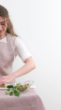 Smiling young woman serving fresh salad on plate. Happy smiling cute woman cooking fresh healthy vegan salad at home with many vegetables in kitchen and trying new recipe High quality photo