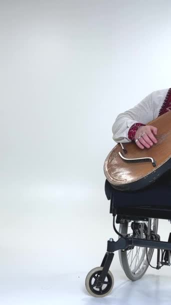 身材矮小 英俊的年轻人 手持科巴扎乐器 坐在轮椅的白色背景上 没有腿 — 图库视频影像