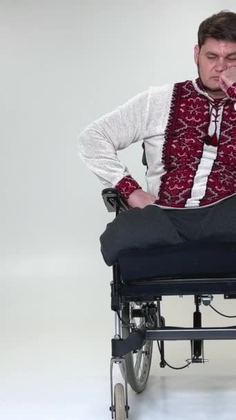 一个英俊的残疾士兵坐在轮椅上与残疾作斗争的老兵身上 年轻的男性看着镜头 神情忧郁 很不高兴 他穿着军服坐在主席职位上 — 图库视频影像