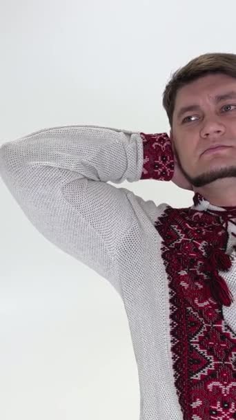 ハンサムな男で刺繍シャツでウクライナの服頭のカメラの後ろに手を置くバックそれは彼が座っていることは明らかであるプル — ストック動画