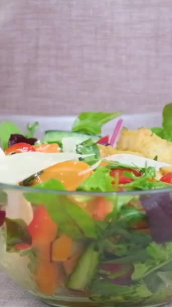 野菜サラダグラスプレートは 野菜のニンジンほうれん草アルグラトマトと混合上に注がれるパルメザンの大きなフレークを木製のスプーンで女性を攪拌 — ストック動画