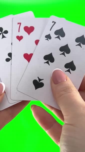 フランスのマニキュアで緑の背景クローズアップ女性の手に4つの77を保持手 女性はカードを並べ替え折り目を調べ同じスートのファン4枚のカードのように広がり — ストック動画