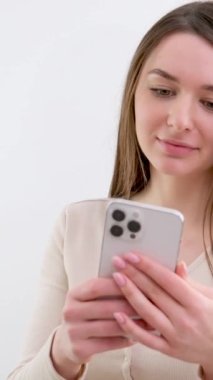 Akıllı telefonlu beyaz bir kızın ellerinde gülümseyen güzel haberler videolar ilginç bilgiler sosyal ağlar beyaz arka plan stüdyo hayatı internette 