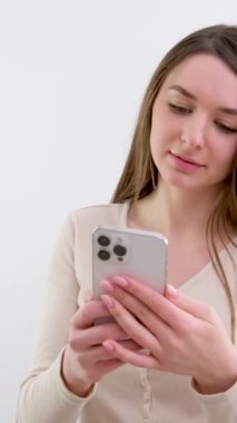 Pembe arka plan stüdyosunda yalnız poz veren turkuaz tişörtlü komik genç kadın. İnsanların yaşam tarzı konsepti. Cep telefonu yazma, SMS mesaj yazma, arama, vay canına, ağzı açık kapatıyormuş.