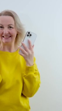 Sarı elbiseli kadın iki numarayı parmakları ve gülümsemesiyle çok mutlu bir şekilde gösteriyor. Gülüşler kazandı. 