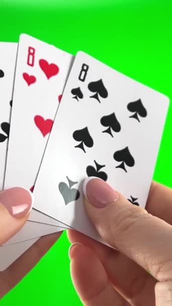 緑の背景に4つの8を保持手クローズアップ女性の手でフランスマニキュア女性ソートカードを介して それらの折り目を検討し 同じスーツの左のファン4枚のカードのように広がる — ストック動画