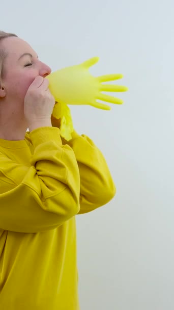 Mão Feminina Segurando Uma Luva Amarela Inflada Isolada Fundo Branco — Vídeo de Stock
