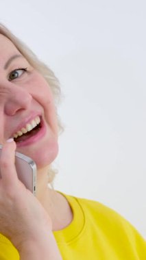 Sarışın bir yetişkin telefonda gülerken samimi ve gerçek bir konuşma beyaz arka planda sarı elbiseler neşe dolu gülümsemeler, neşeli gözler
