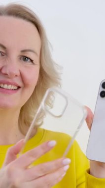 Apple iPhone 13 'ü ara. Maksimum güvenlikli kadın akıllı telefonuna şeffaf bir çanta takıyor. Beyaz arka plan. 