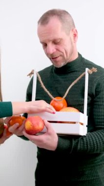 Orta yaşlı erkek satıcı mandalina elmalı hindistan cevizi alması için kıza teklif ediyor. Satıcıyı dinliyor, vejetaryen keltoş adamı dinliyor.