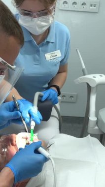 Dişçi ve bayan asistan dişleri dökülmüş hastayı muayene ediyor. Doktor ve stajyer, protez için dişçi muayenehanesinde müşteriyle birlikte çalışıyor. Erkek dişçi randevusu Ukrayna Vinnitsa Diş Hekimliği 12.2022