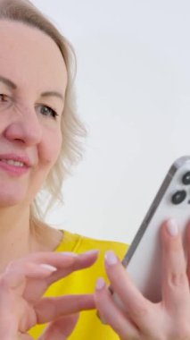 Akıllı telefon tutan beyaz kadın göz yorgunluğu çekiyor, esmer kız kuru gözlerde ağrıdan muzdarip, kötü görme sorunu, mavi arka plan stüdyosunda izole edilmiş. Yüksek kalite