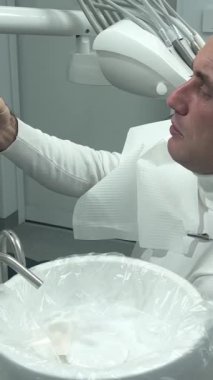 Tuvalette ağız gargarası kullanan bir adamın yakın çekimi. Diş bakımı konsepti. Dişlerini fırçaladıktan sonra prosedür. Antibakteriyel ağız sıvısı. Döküyor, duruluyor ve tükürüyor. Adam aynaya bak.