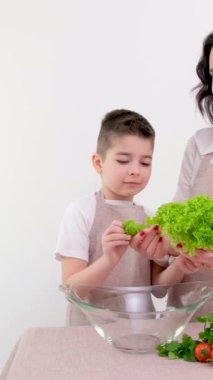 Anne ve oğlu salata hazırlıyor. Mutfakta taze sebzeli genç bayan. Yüksek kalite fotoğraf