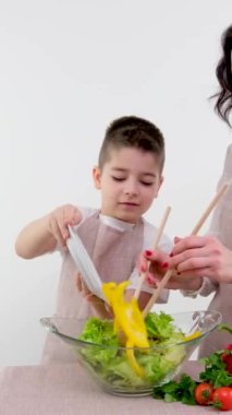 Anne oğluna salata yapmayı öğretiyor. Sarı biber tabağı ekliyor. Sağlıklı vejetaryen yemek vitaminleri öğreniyor. 
