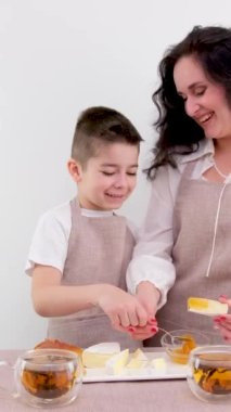 Anne ve küçük oğlu peynirle kaplanmış ballı kahvaltı beyaz arka planda sağlıklı yemekler çay mutfağı önlüğü