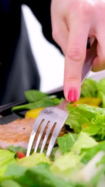A girl eats vegetable salad with a fork from a white plate. Close up shot. High quality 4k footage