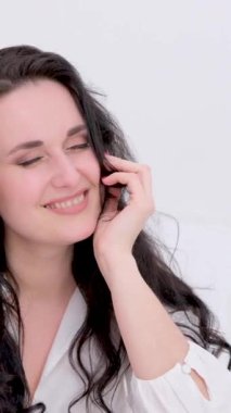 Şefkat ve güzellik zihni ve güç güzel esmer gözlerini kapar beyaz bir arka planda gülümserken beyaz çarşaflar içinde narin cilt reklamları yaparak. 