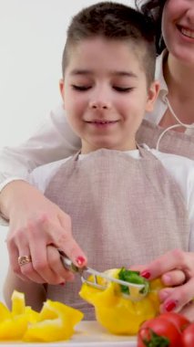 Mutlu anne ve küçük çocuk evcil mutfakta birlikte sebze ve yiyecek hazırlıyorlar. Anne küçük oğluna mutfakta yemek yapmayı öğretiyor.