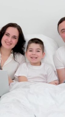 Erkek kadın çocuk tatilde yatakta birlikte vakit geçirir. Keyfinize bakın. Tabletlere bakın. 