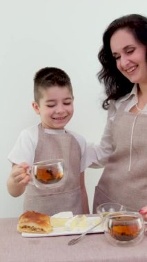 Anne ve oğul çay içip çörek ve kruvasan yiyorlar. Yüksek kalite 4k görüntü