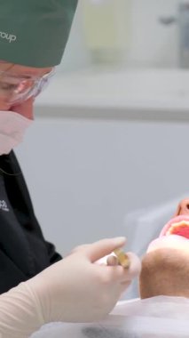 Bir diş kliniğinde ameliyat. Diş hekimi yarayı hastanın ağzına dikiyor. Yara dişçisini dikin. Yüksek kalite 4K görüntü Ukrayna 2023
