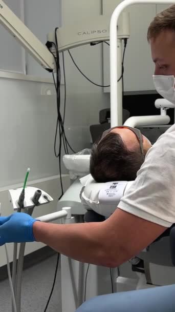 Man Förbereder Maskin För Rengöring Tänder Patienten Sitter Stolen Bredvid — Stockvideo