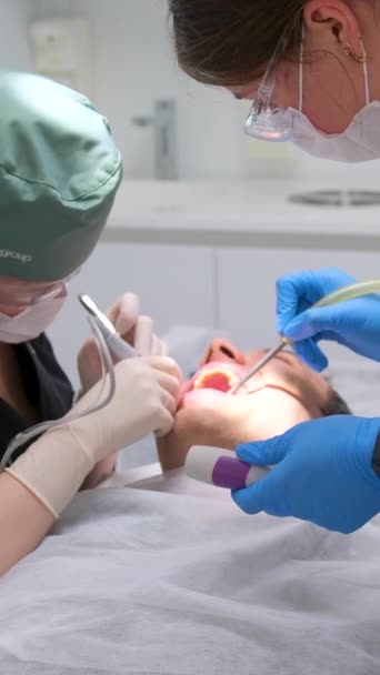 歯医者と助手は患者を治療する 現代の歯科における歯科治療 歯の抽出手順を受けて歯科椅子で患者のクローズアップショット ウクライナ2023 — ストック動画