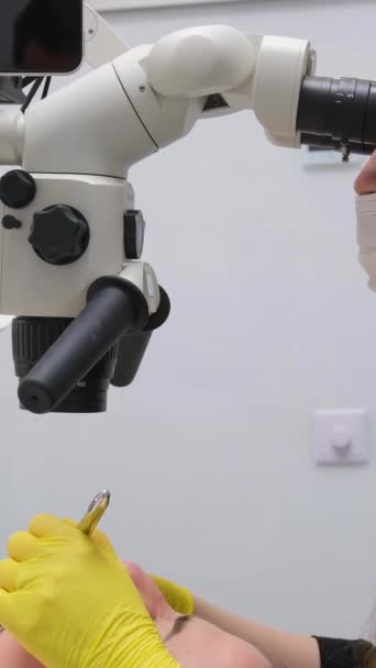 歯科医院最新機器と技術女性医師は テキストのための大きなタブレット画面の白い背景スペースを持つ顕微鏡を使用して患者の歯を扱います — ストック動画