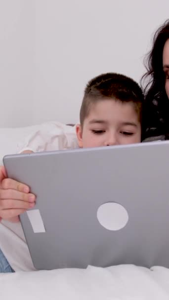 快乐的年轻妈妈教可爱的儿子在家里用智能手机学习有趣的应用程序 微笑的妈妈抱着学龄前的男孩玩着好玩的看手机放松 — 图库视频影像