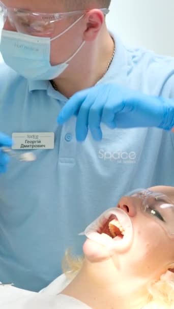 歯医者で青い手袋のクローズアップは 女性の口を修正口を開く治療歯を透明ガラスで保護目をきれいに歯を白く — ストック動画