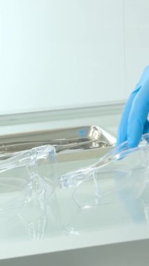 Aynı zamanda doktor hemşire cam masaya plastik şeffaf gözlük ve stomatoloji hastanesi için gerekli aletleri koydu. Mavi eldivenler steril koruyucu gözlükler. 