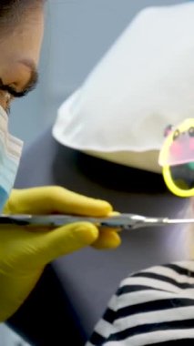 Küçük kızın ve doktorun maske takan sarı hijyenik eldivenli dişçi dişçi çocuk dişçisi gözlüklü oyuncak ayı gözlü kız. 