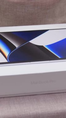 Kadın elleri, Apple 'dan gelen MacBook 14 Pro' nun beyaz kutusunu M1 ev hanımı önlüğü mutfak önlüğüyle açıyor. 