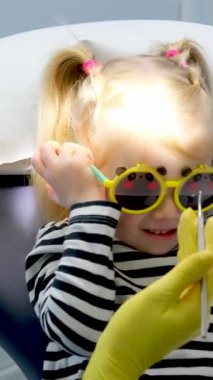 Maskeli küçük bir kız ve doktorun yakın çekimi sarı hijyenik eldivenli dişçi dişçi çocuk dişçisi gözlüklü oyuncak ayı gözlü kız 