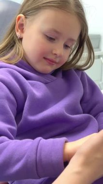 hold the hand, be afraid of the dentist Lovely little kid smiling while talking with the pediatric dentist after doing a tenth examination in a pediatric stomatology cute little girl sits dental chair