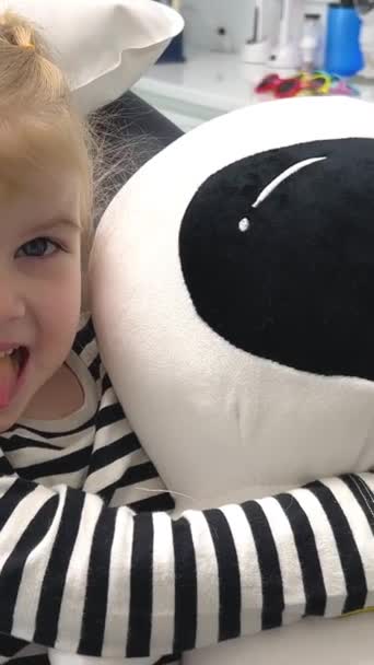 Маленька Дівчинка Смугастій Блузці Стоматологічному Кріслі Показує Язик Дивиться Нас — стокове відео