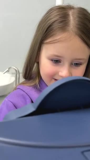 娱乐中心的小女孩 孩子们在代币游戏机上玩耍穿着淡紫色运动服的小女孩笑着玩相机慢慢地漂浮着慢动作的牙医办公室 — 图库视频影像