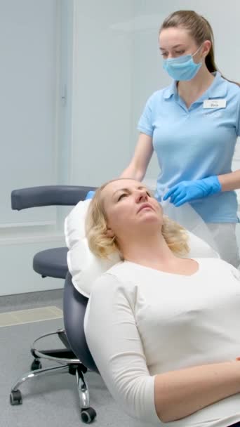 一个女人躺在椅子上等待牙科手术男医生和护士站在旁边 一边想一边戴着口罩手套清洁身体 — 图库视频影像