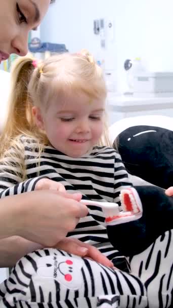 第一次刷牙课小女孩穿条纹毛衣刷牙玩具斑马医生护士展示了如何 — 图库视频影像