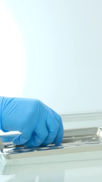 手拿着手套把牙科器械放在一个小金属盘子上 医务人员正在准备口腔科检查工具 靠近点高质量的4K镜头 — 图库视频影像