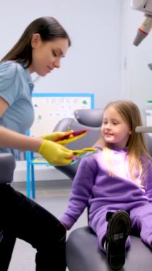 Mavi sabahlıklı genç kız dişçi koltuğunda oturuyor. Kavram, dişçide bir çocukla oynamak.