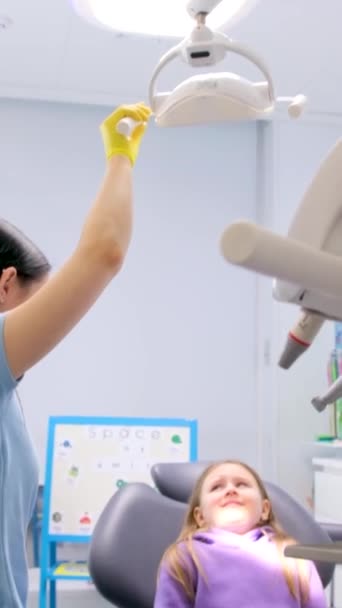 Γιατρός Οδοντίατρος Κατευθύνει Φως Στα Κορίτσια Πρόσωπο Στο Οδοντιατρικό Γραφείο — Αρχείο Βίντεο