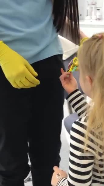 4岁的女孩第一次到牙科诊所看病时 一位戴黄色手套的医生送给女孩太阳镜 — 图库视频影像