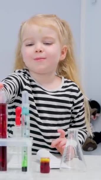 穿着条纹毛衣的女孩在化学实验室里选择一个涂有红色油漆的试管 用于教学龄前儿童物理化学实验室 — 图库视频影像
