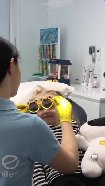 Παιδιατρικός Οδοντίατρος Γιατρός Βάζει Κίτρινα Γυαλιά Ηλίου Στο Κορίτσι Ένα — Αρχείο Βίντεο